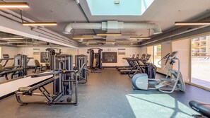Ein Fitnessraum mit unterschiedlichen Trainingsgeräten, einer Uhr und einem Schild mit der Aufschrift 'GYM MODE ON'.