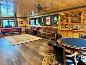 A spacious living room with a pool table, comfortable seating, and sports memorabilia.