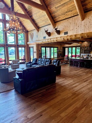 A spacious living area with a large sectional sofa, a fireplace, and a view of the outdoors through large windows.