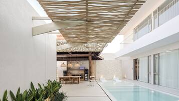 Een modern binnenzwembad met een houten pergola, een bar en een stenen muur.