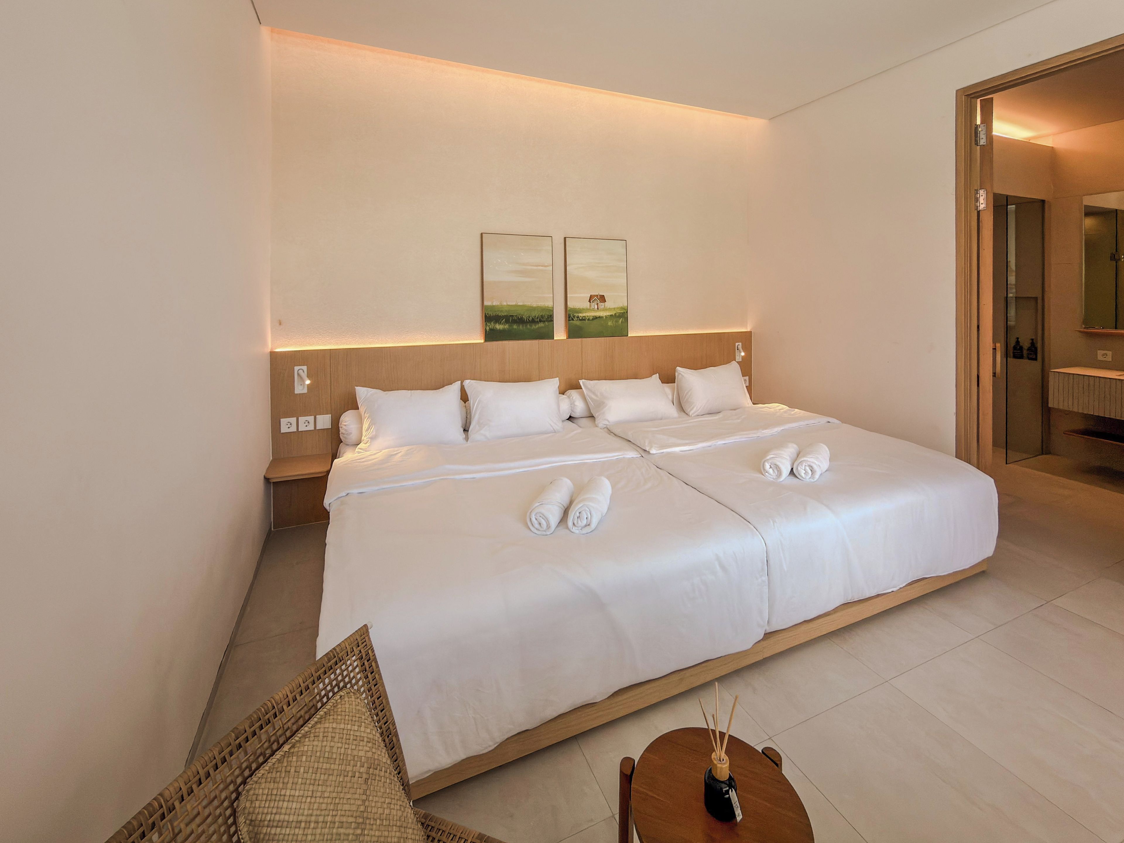 Une chambre d’hôtel avec un grand lit, une table de chevet, une chaise et une petite table sur laquelle se trouve une bouteille.