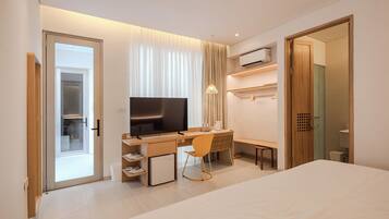 Ein modernes Hotelzimmer mit einem Bett, einem Schreibtisch mit Stuhl, einem Fernseher und einem Kleiderschrank.