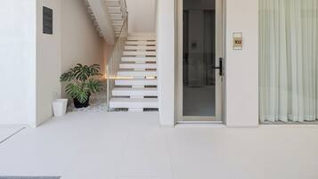 Een modern interieur met een trap naar een tweede verdieping, een glazen deur met een nummer en een potplant.