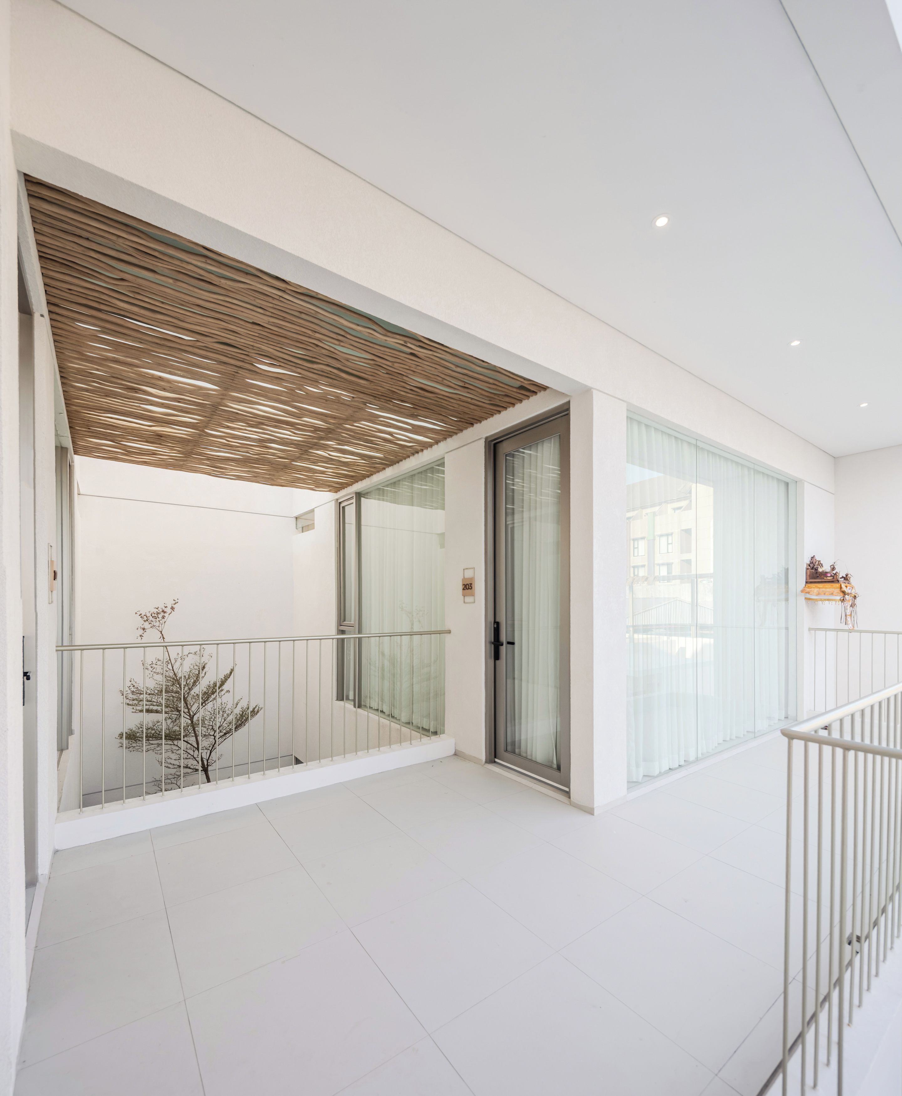 A modern interior with a balcony, glass doors, and a white tiled floor.
