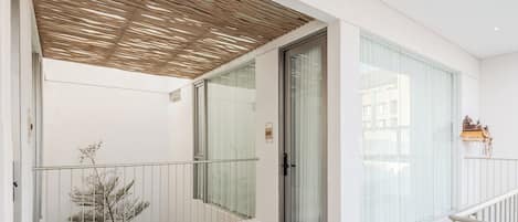 Interior moderno com varanda, portas de vidro e piso revestido de azulejos brancos.