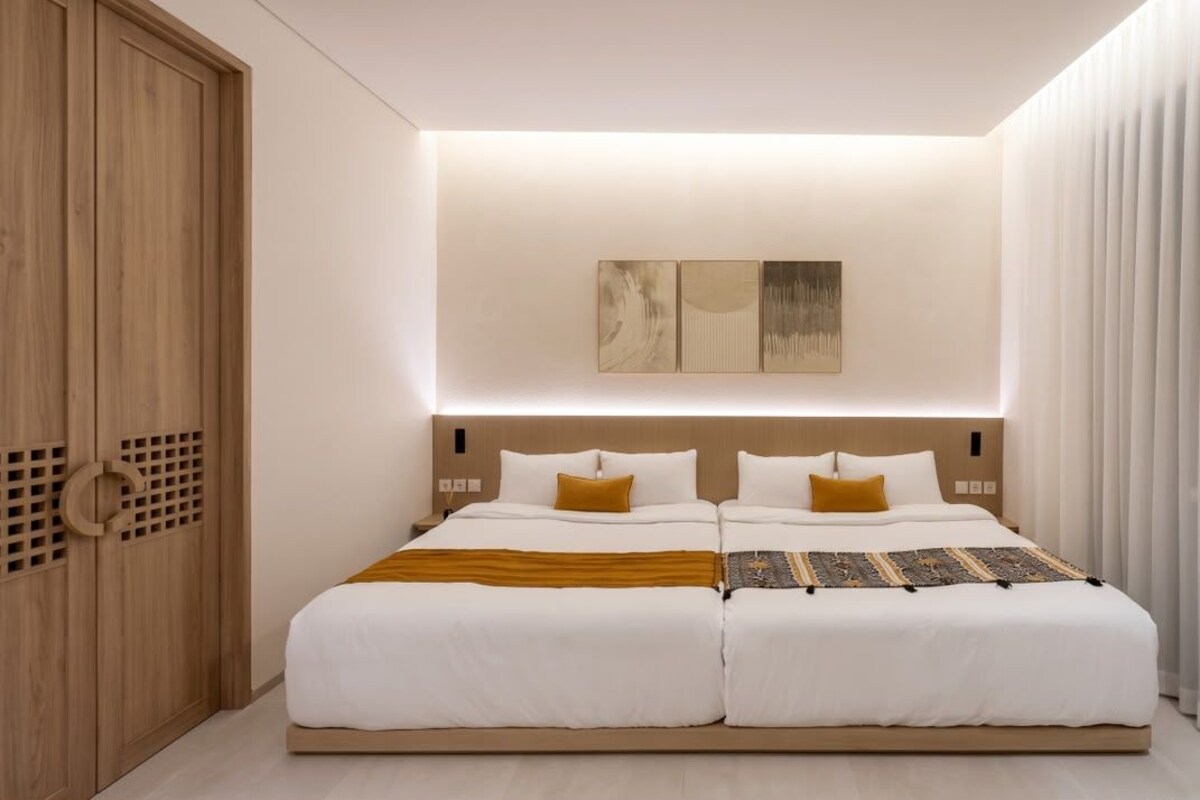 Un dormitorio moderno con dos camas, un armario de madera y una obra de arte colgada en la pared.