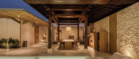 A pool area with a covered seating area and a stone wall.
