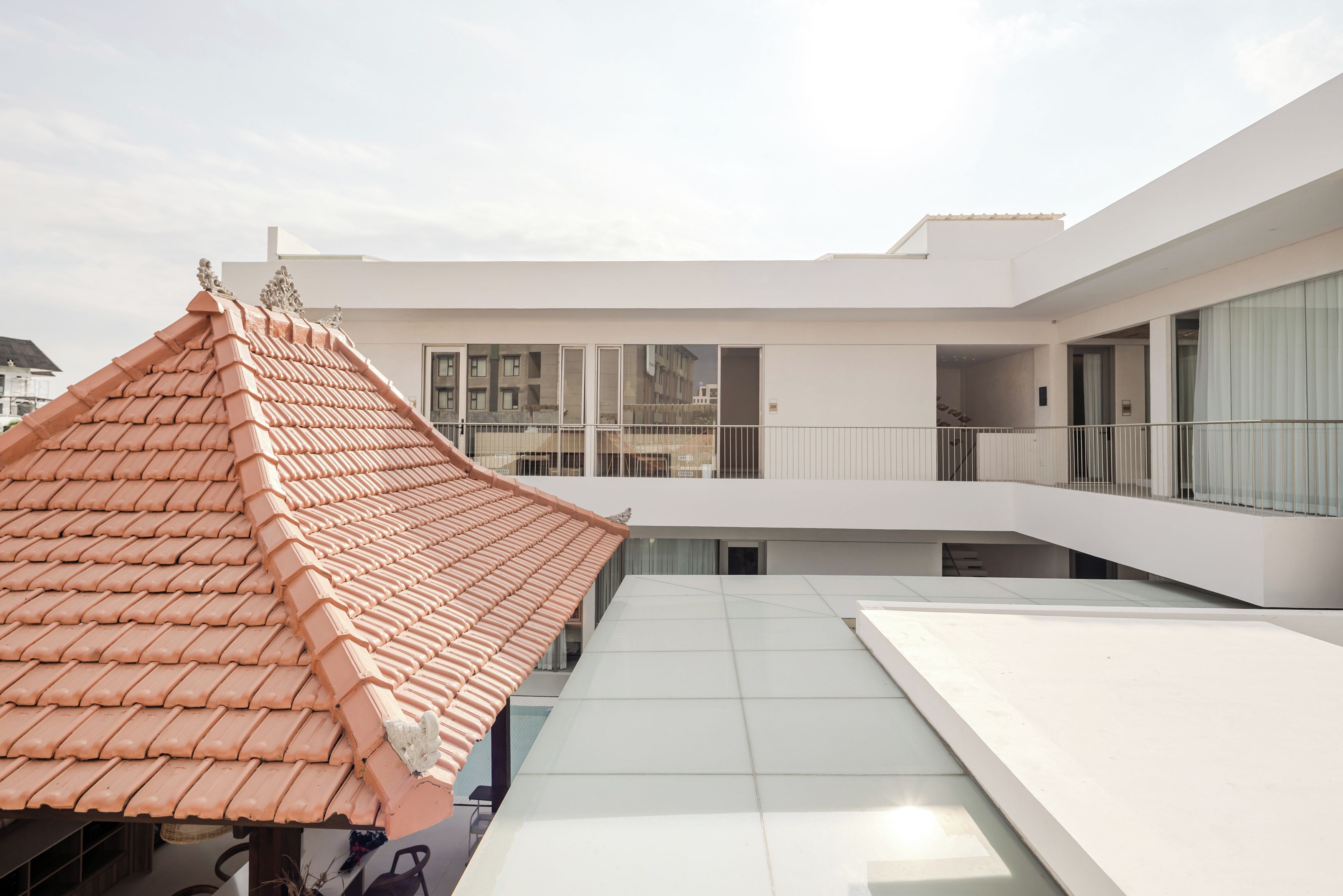Un bâtiment moderne doté d’un toit traditionnel recouvert de tuiles et d’un étage supérieur plat, de couleur blanche.