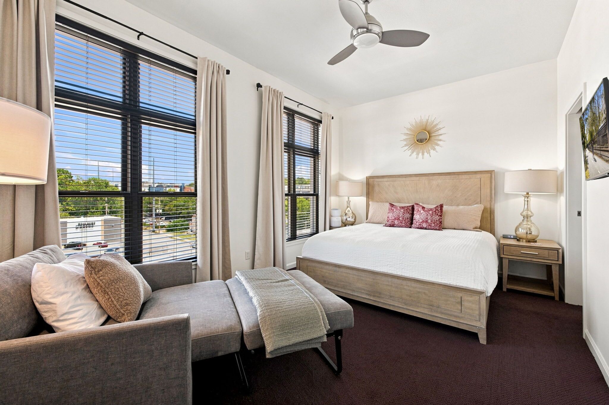 Habitación de hotel con cama, sofá, escritorio y ventilador de techo.
