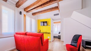 A modern living space with a red sofa, a yellow accent wall, and a staircase leading to another room. - Suite Mondrian 100m from Biennale - Canal View (Venezia)