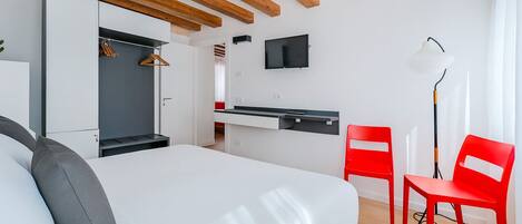 Un dormitorio moderno con cama, escritorio y televisor.