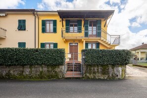 A two-story building with a yellow facade, green shutters, and a gated entrance. - [Appartamento Roberto] 4 beds + A/C (Santo Stefano di Magra)