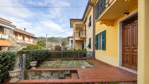 A courtyard with a paved pathway, a small water feature, and a staircase leading to a building with a wooden door. - [Appartamento Roberto] 4 beds + A/C (Santo Stefano di Magra)