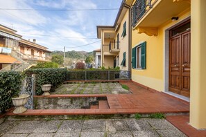 A courtyard with a paved pathway, a small water feature, and a staircase leading to a building with a wooden door. - [Appartamento Roberto] 4 beds + A/C (Santo Stefano di Magra)