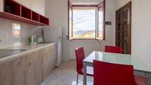 A compact kitchen with a window, a dining table with red chairs, and a view of the outside. - [Appartamento Roberto] 4 beds + A/C (Santo Stefano di Magra)