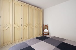 A bedroom with a large wardrobe, a bed with a checkered bedspread, and a small chair. - [Appartamento Roberto] 4 beds + A/C (Santo Stefano di Magra)