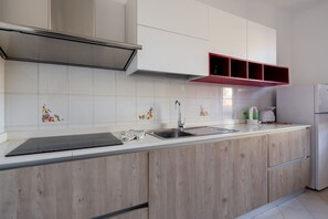A modern kitchen with a stainless steel sink, wooden cabinets, and a red shelf above the countertop. - [Appartamento Roberto] 4 beds + A/C (Santo Stefano di Magra)