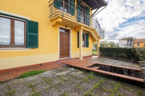 A yellow building with a wooden door, a balcony, and a paved courtyard. - [Appartamento Roberto] 4 beds + A/C (Santo Stefano di Magra)
