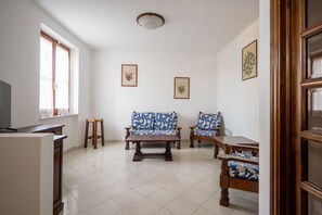 Ein Wohnzimmer mit einer Couch, Sesseln, einem Couchtisch und einem Fernseher.