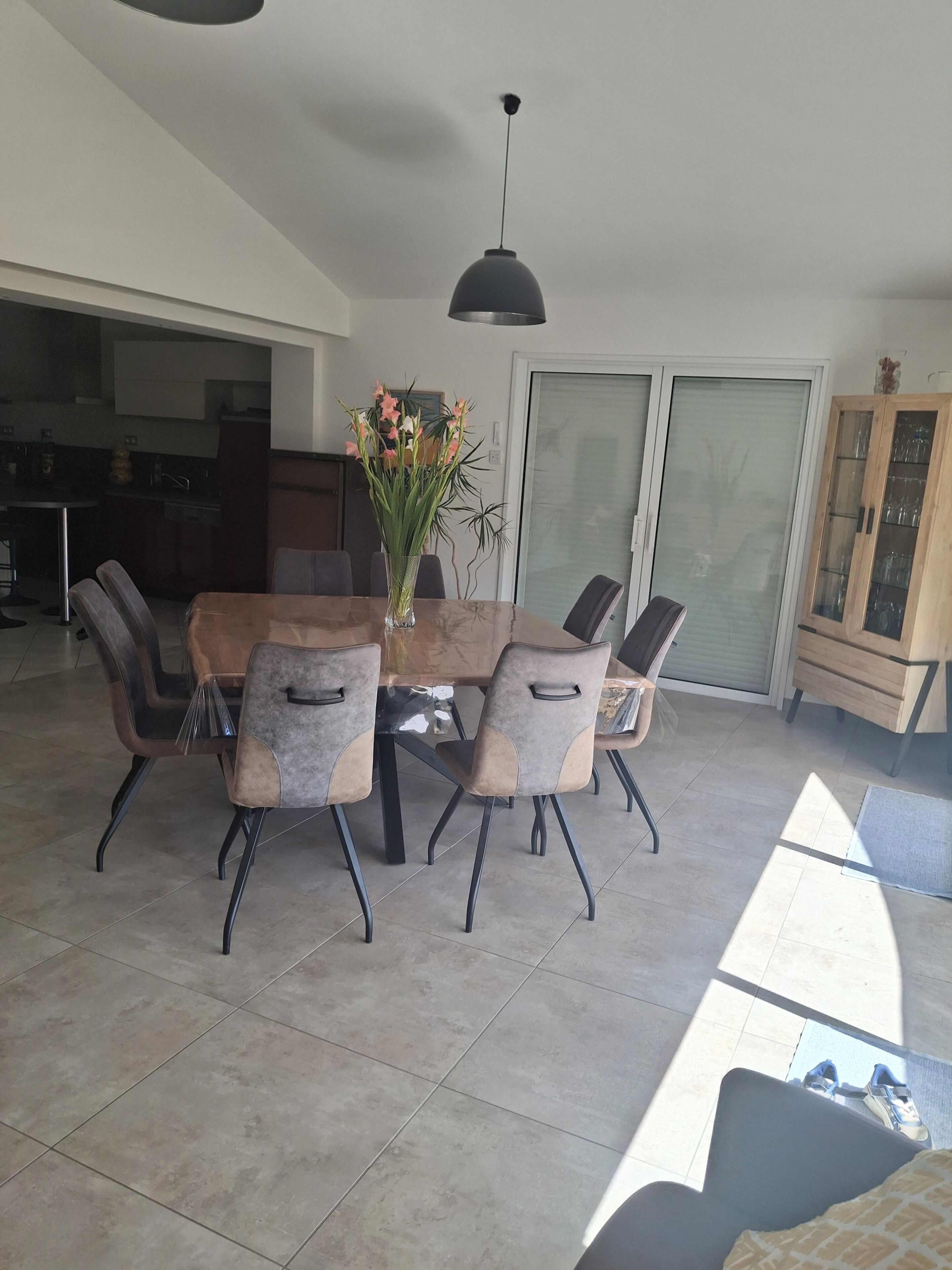 Un coin repas avec une table et des chaises, un vase de fleurs et un luminaire au plafond.