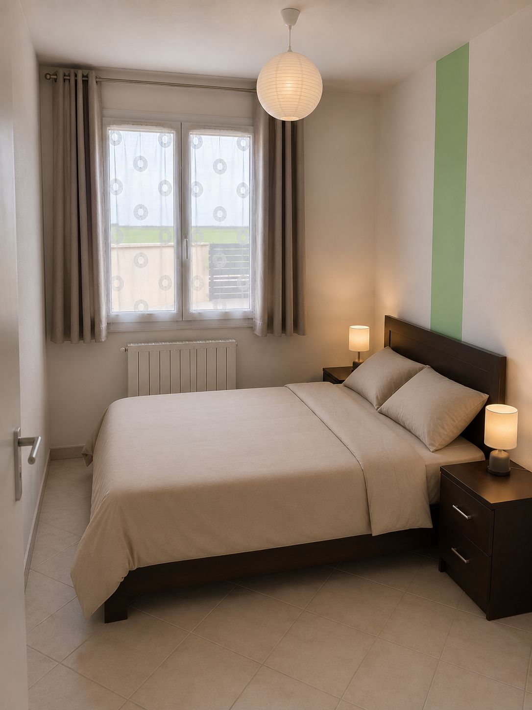 A bedroom with a bed, two bedside tables, a window with curtains, a radiator, and a hanging light fixture.