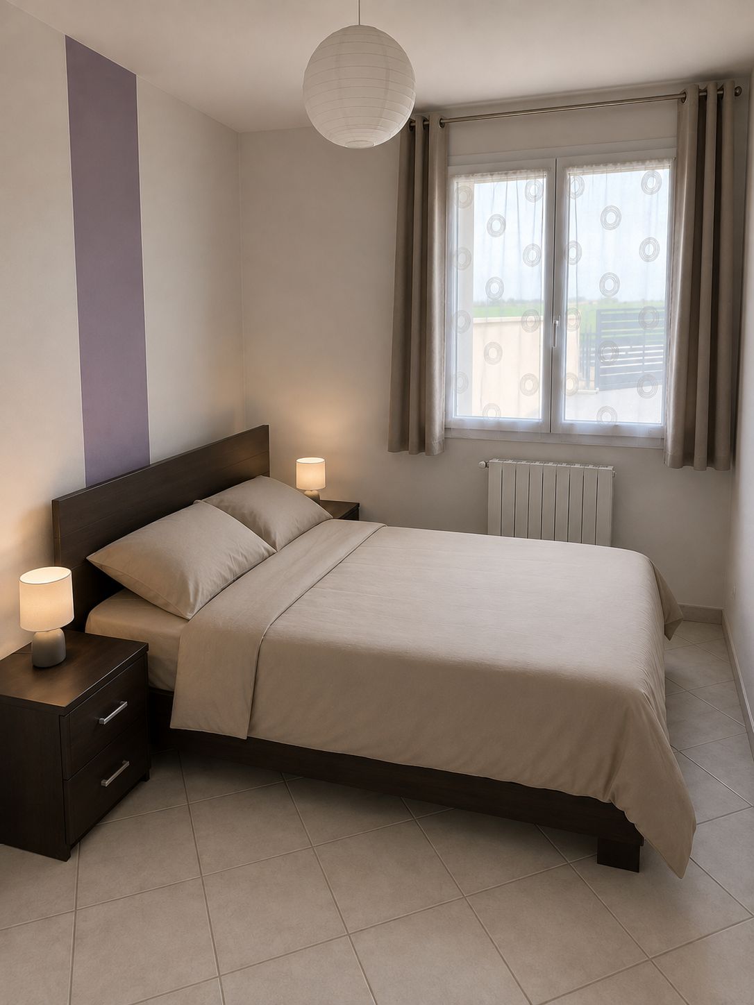 Un dormitorio con cama, mesitas de noche, lámpara, radiador y ventana con cortinas.