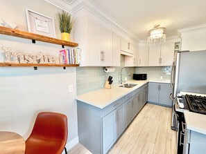 A modern kitchen with white cabinets, a stainless steel sink, and a built-in stove. - Cozy Cottages, Min 2 Beach, Shops & Restaurants! (San Diego)