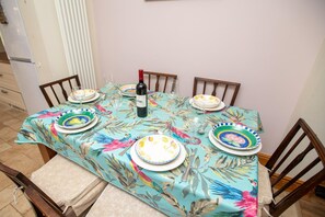 Mesa de comedor lista con platos, vasos y una botella de vino.