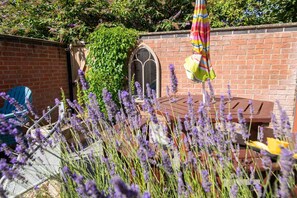 A brick wall with a wooden bench and a hanging umbrella. - Large Family House close to Cathedral Quarter - Pass the Keys (Lincoln)