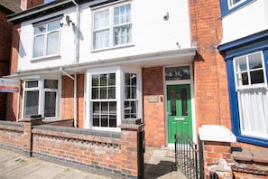 A two-story residential building with a green door, white-framed windows, and a brick facade. - Large Family House close to Cathedral Quarter - Pass the Keys (Lincoln)