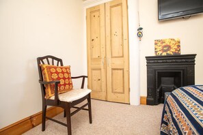 A room with a wooden chair, a fireplace, and a television mounted on the wall. - Large Family House close to Cathedral Quarter - Pass the Keys (Lincoln)