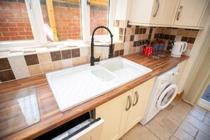 A kitchen with a white sink, wooden countertop, and a washing machine. - Large Family House close to Cathedral Quarter - Pass the Keys (Lincoln)