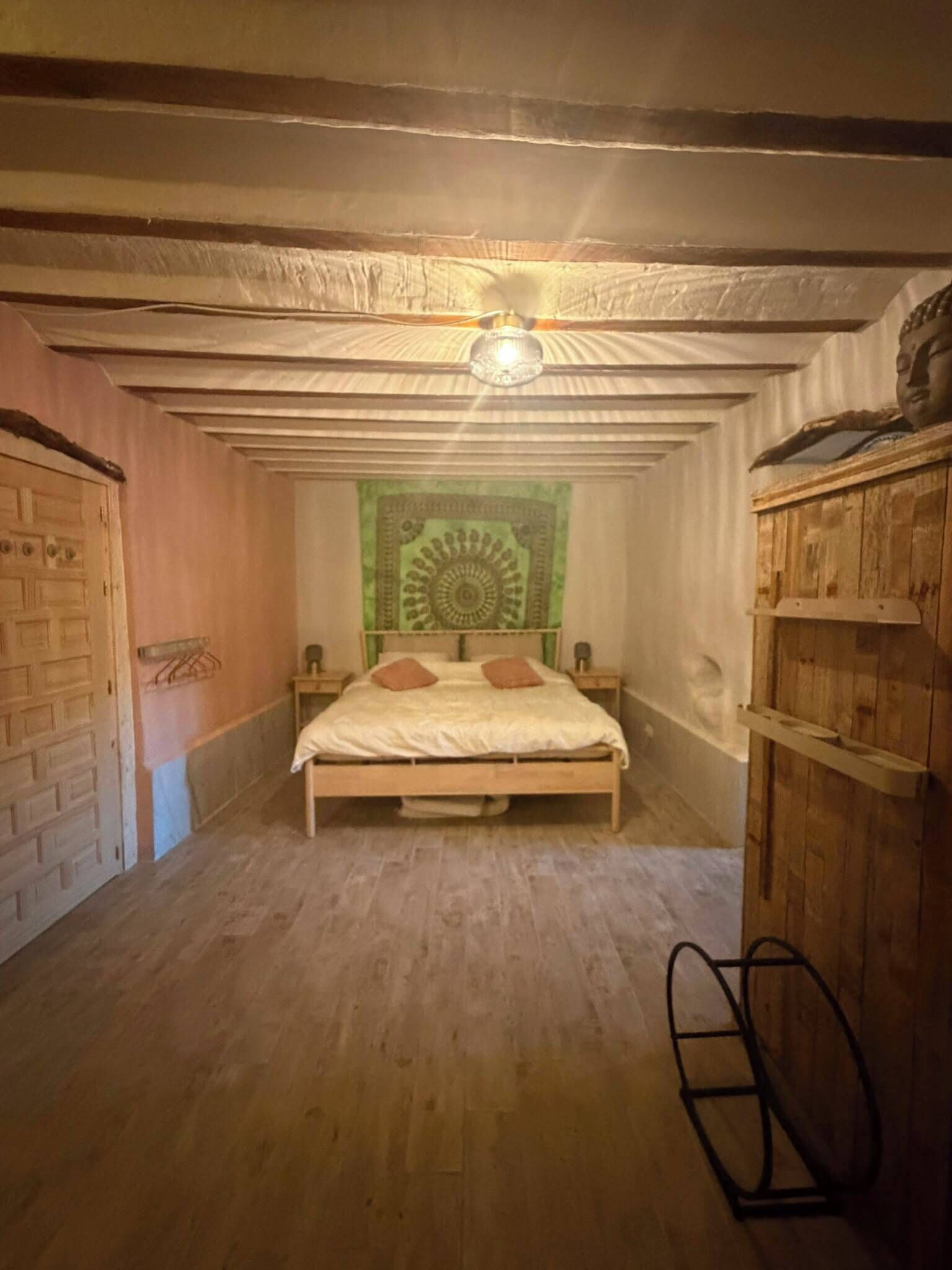 Une pièce avec un lit, une tapisserie et des poutres en bois au plafond.