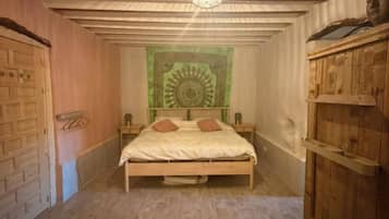 Une pièce avec un lit, une tapisserie et des poutres en bois au plafond.