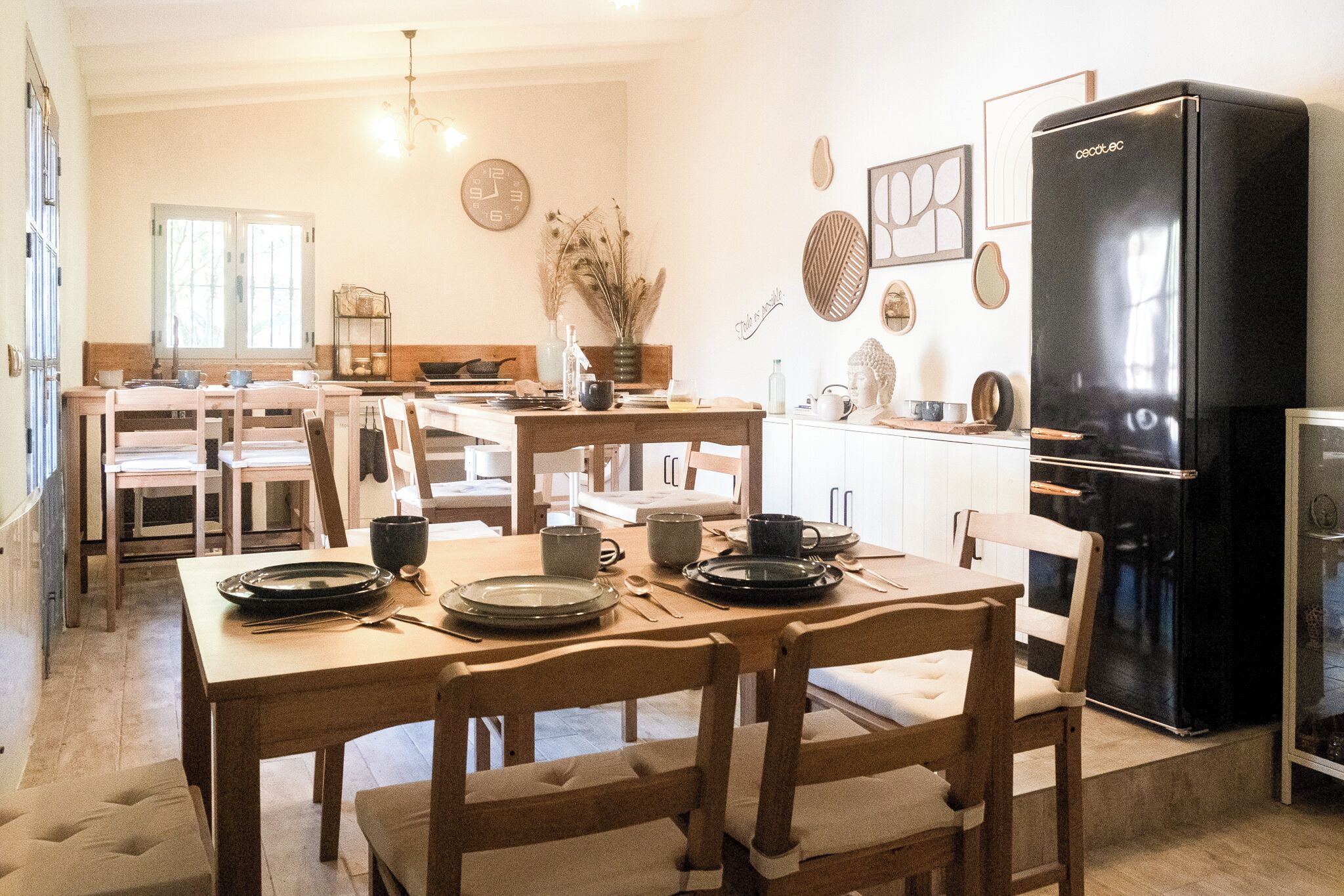 Une cuisine avec des meubles en bois, un réfrigérateur noir et divers ustensiles de cuisine disposés sur le plan de travail.