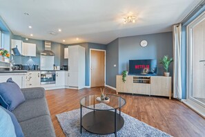 Eine moderne Wohnung mit Küche, Wohnzimmer und einem Fernseher, der 'NETFLIX' anzeigt.