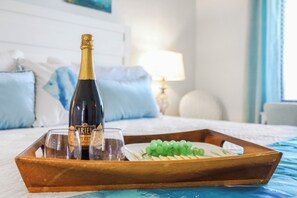 Eine Champagnerflasche, zwei Gläser und ein Tablett mit grünen Trauben auf einem Bett.