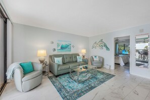 Ein Wohnzimmer mit Sofa, Ohrensessel, Couchtisch und einem Teppich.