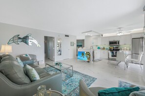 Uma sala de estar moderna com um sofá cinza, uma mesa de centro de vidro e um tapete azul estampado.