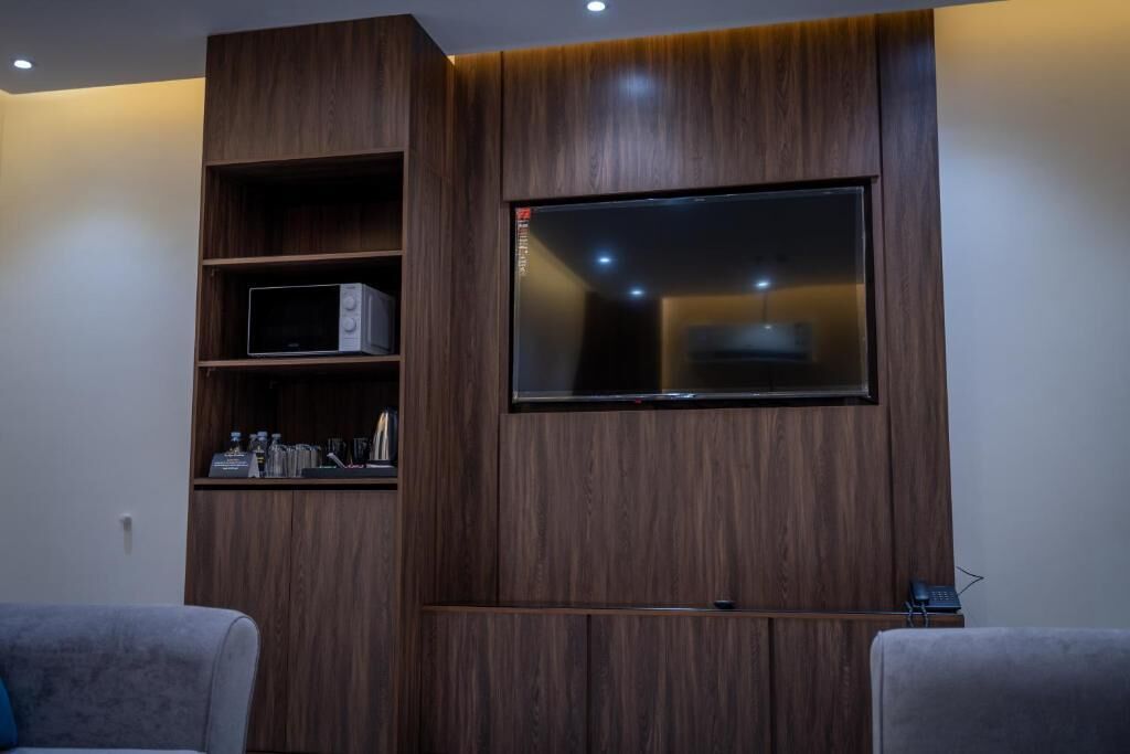 Un salón moderno con televisor empotrado, estanterías de madera y televisor de pantalla plana montado en la pared.
