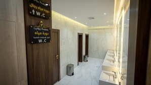 Un baño moderno con suelo de mármol, una puerta de madera y un letrero que indica un inodoro Prolative.