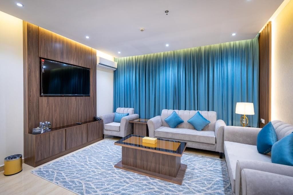 Una sala de estar moderna con un televisor de pantalla plana, dos sofás, una mesa de centro y una alfombra estampada.