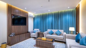 Una sala de estar moderna con un televisor de pantalla plana, dos sofás, una mesa de centro y una alfombra estampada.