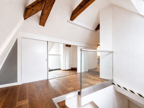 A modern interior with a wooden floor, white walls, and a glass railing. - Old Prague Charm | Historic 2BR by Charles Bridge (Prague 1)