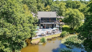 Un edificio sul fiume con posti a sedere all'aperto e una terrazza con vista sull'acqua.