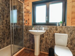 A bathroom with a glass shower enclosure, a pedestal sink, and a toilet. - The Log Cabin (Ormskirk)