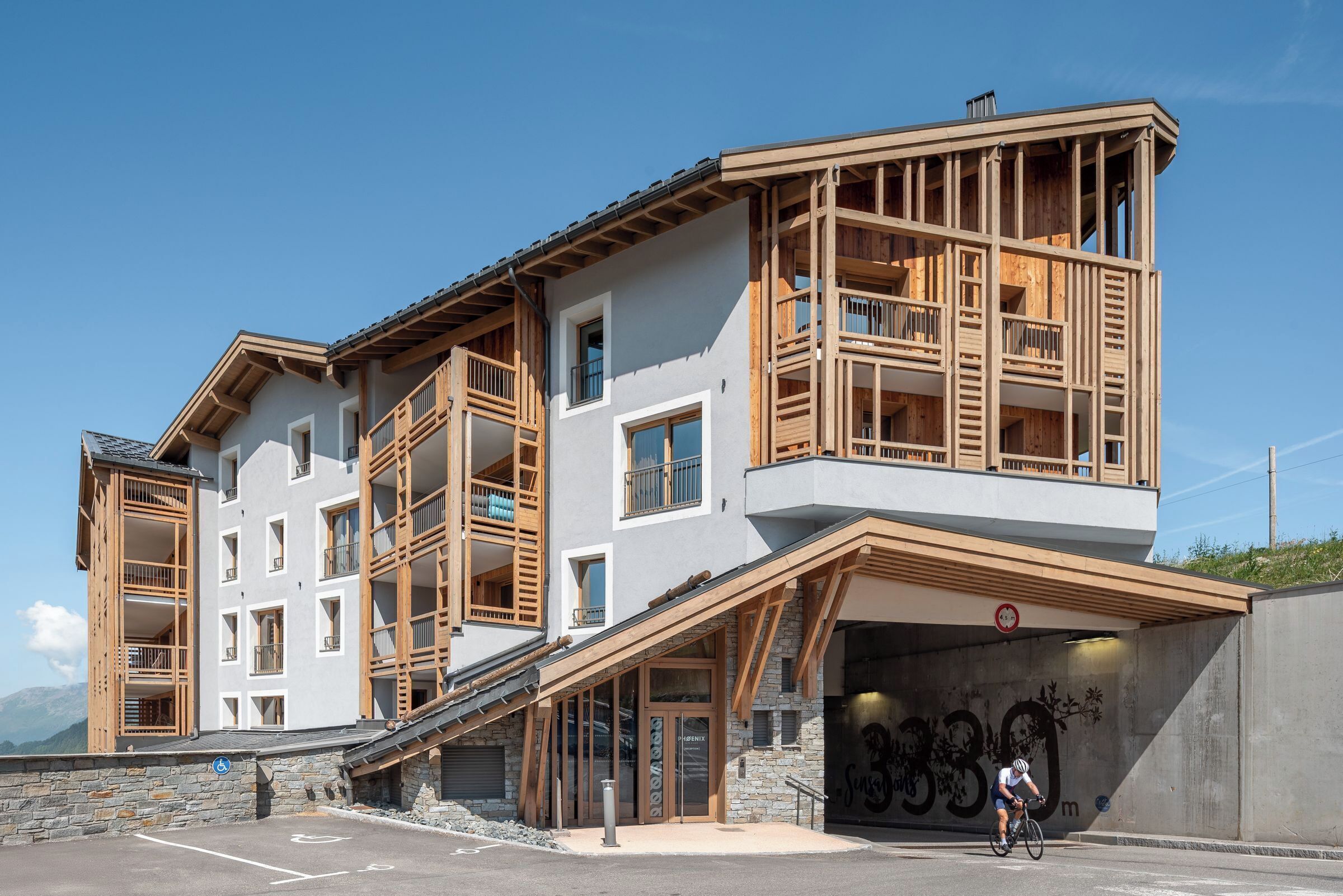 Un edificio de varios pisos con un telesilla, balcones de madera y una entrada cubierta.