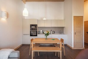 Eine moderne Küche mit weißen Schränken, einem Holztisch und einer Bank.