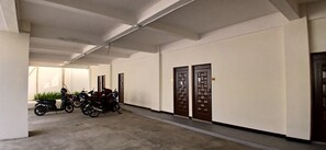 Un pasillo con una hilera de puertas cerradas a un lado y motocicletas estacionadas al otro.