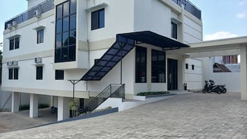 Un bâtiment moderne doté d’un escalier, de climatiseurs et d’une entrée abritée.
